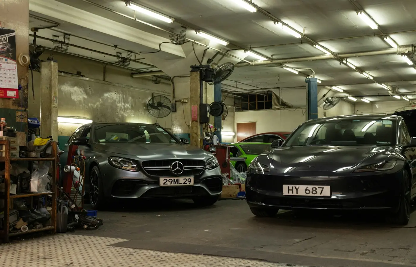 Two luxury cars parked inside a dimly lit industrial automotive repair garage